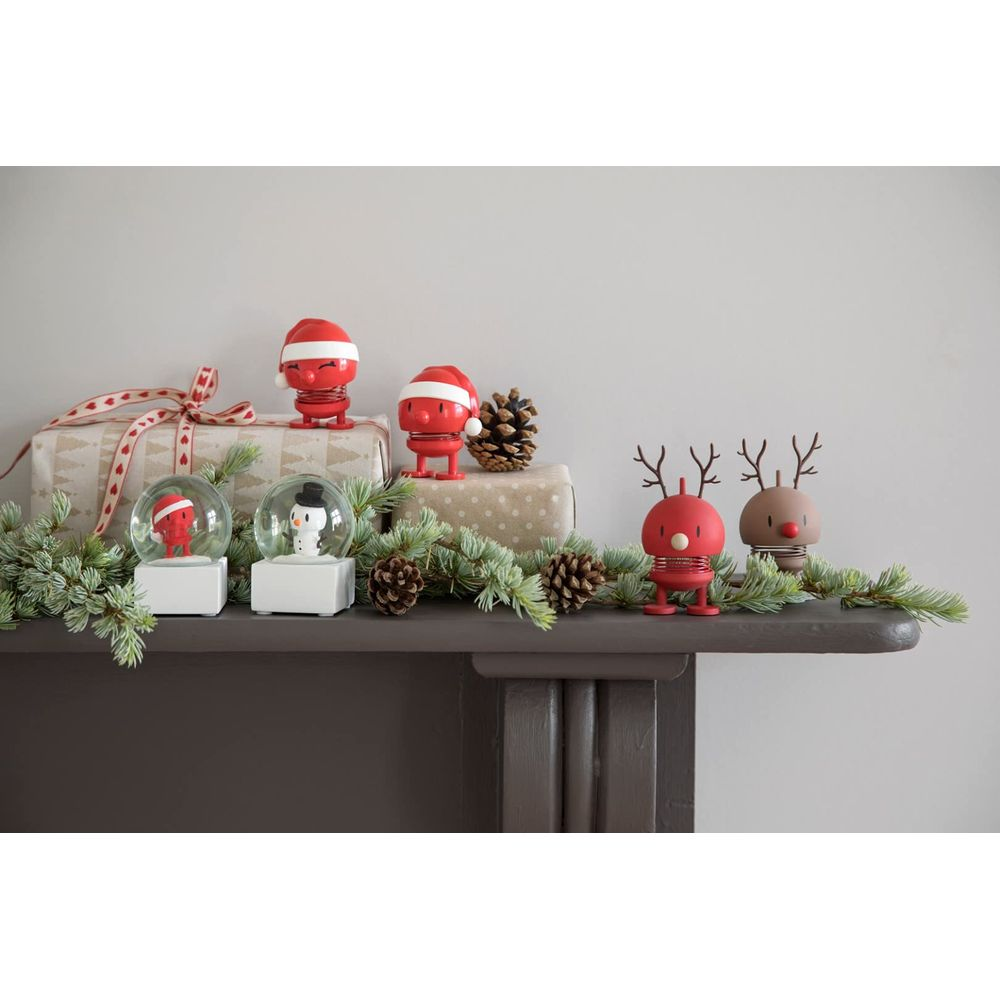 Weihnachtsdekoration auf einem Kaminsims mit Figuren, Geschenken und Tannenzapfen.