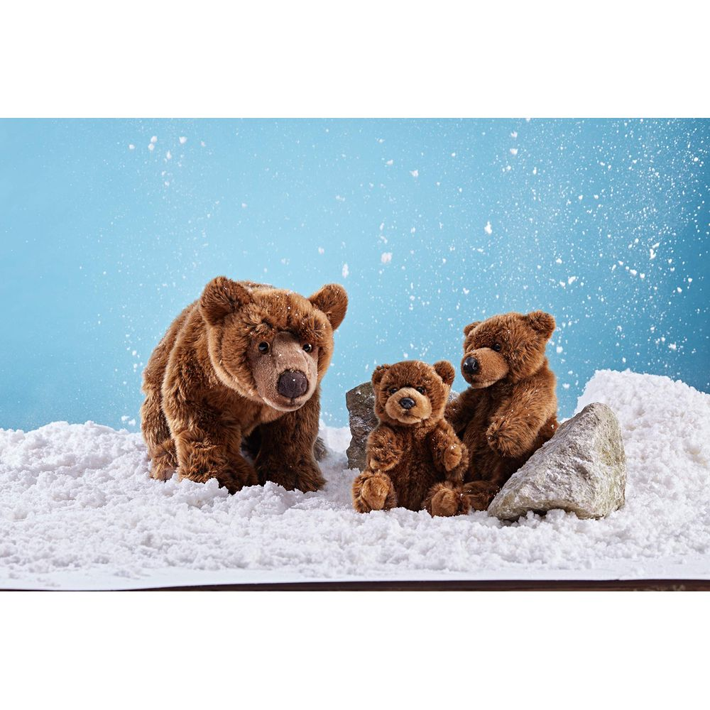 Drei braune Teddybären im Schnee vor blauem Hintergrund mit weißen Flocken.