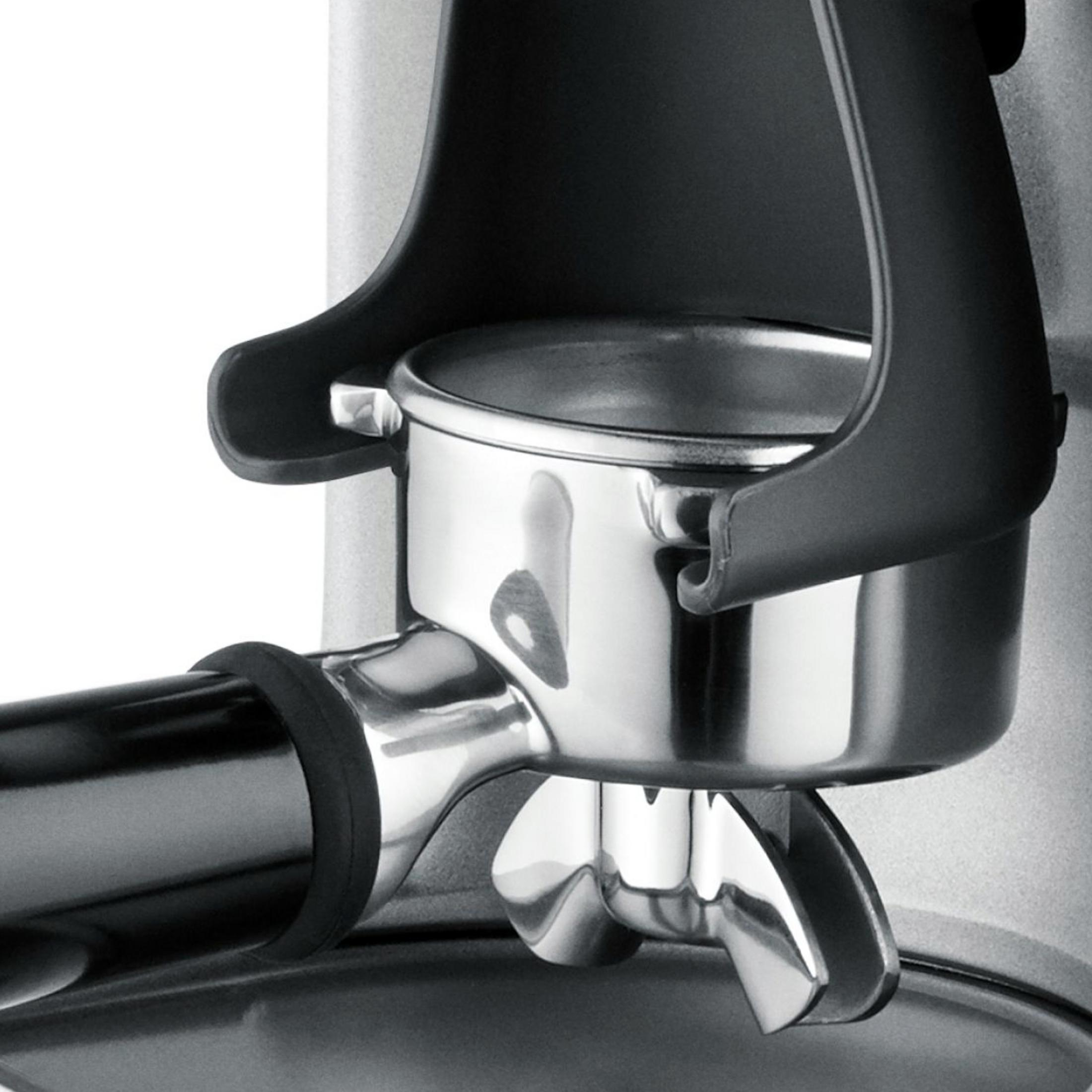 Primo piano del gruppo erogatore di una macchina da caffè in metallo lucido e plastica nera.