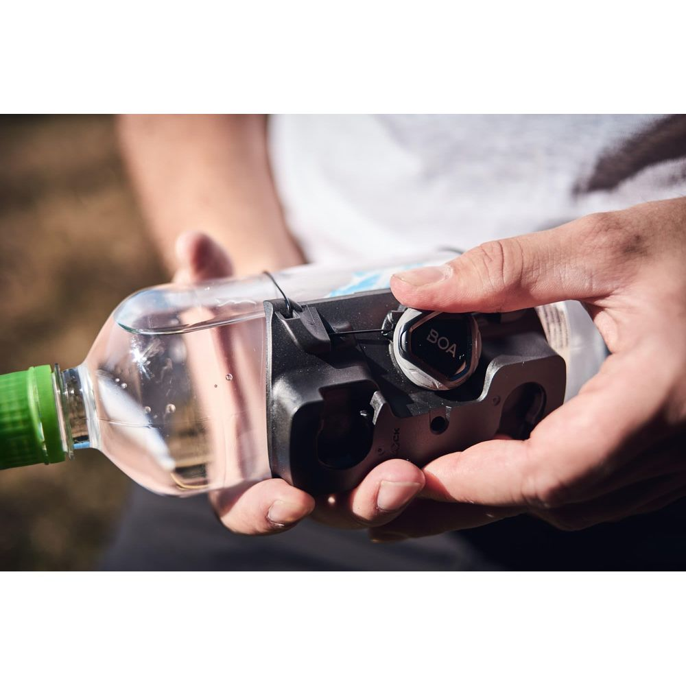 Hände halten eine Wasserflasche mit einem schwarzen BOA-Verschlussmechanismus.
