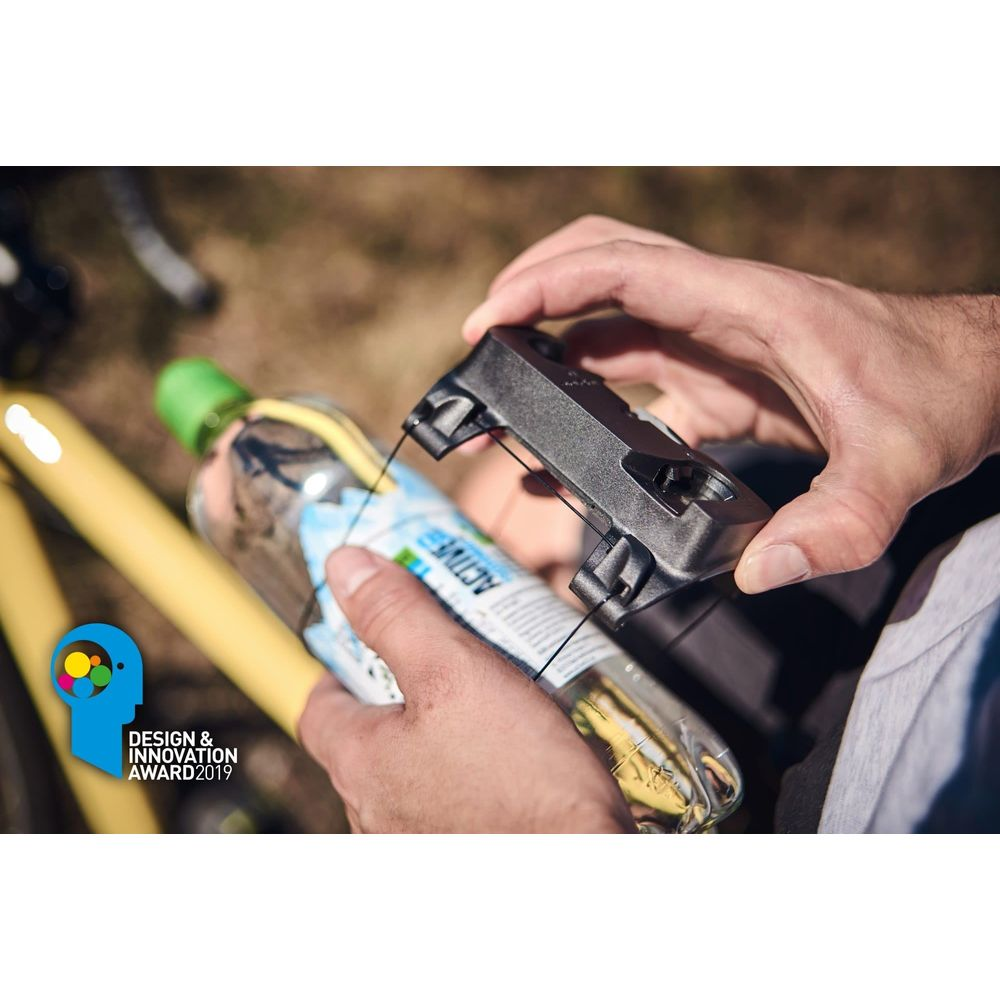 Eine Hand hält einen schwarzen Fahrradhalter über einer Wasserflasche.