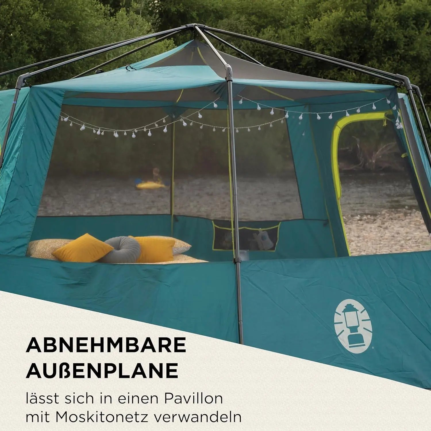 Ein türkiser Pavillon mit Lichterkette und Kissen im Inneren, draußen im Grünen.