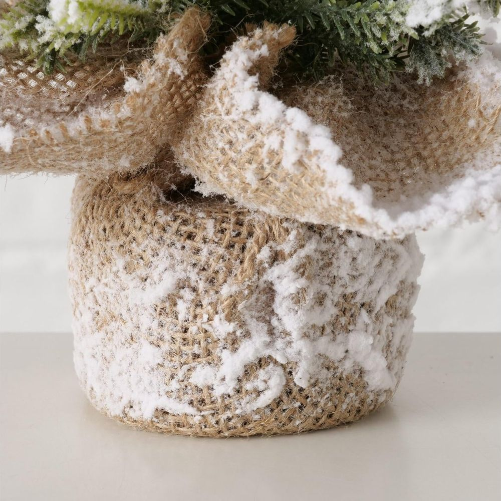 Ein mit Schnee bedeckter Weihnachtskranz aus Jute, der auf einem Tisch steht.