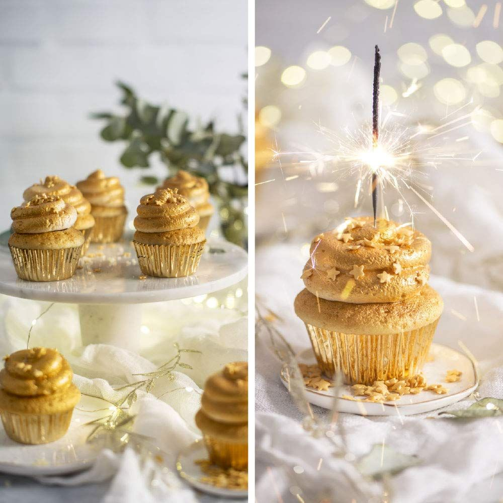 Goldene Cupcakes mit Sternen und einem Wunderkerze.