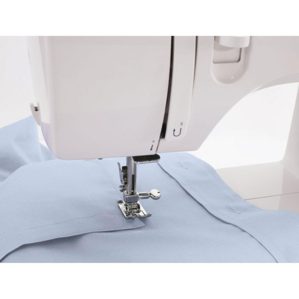 Eine weiße Nähmaschine näht hellblauen Stoff mit sichtbaren Knöpfen.