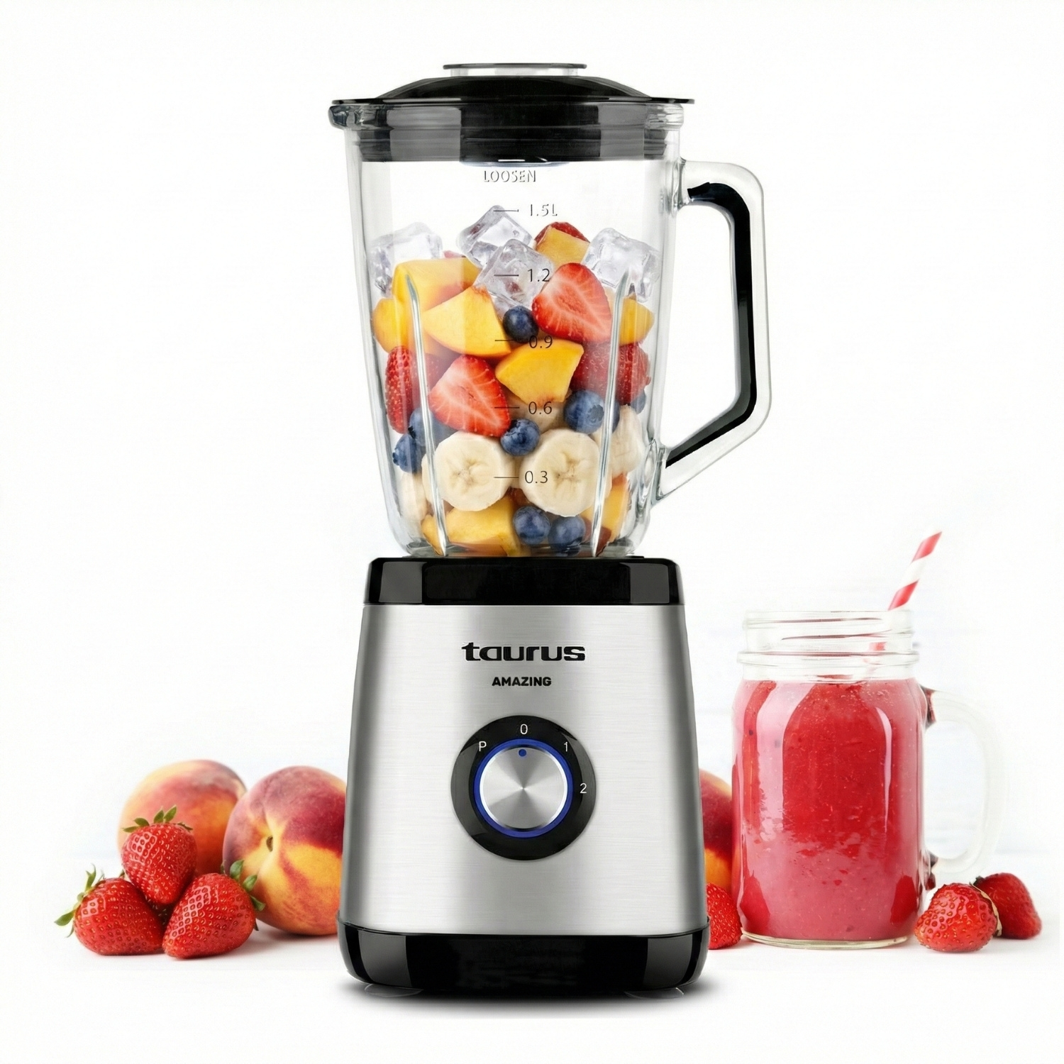 Una licuadora con frutas y hielo, al lado un vaso de batido y frutas.