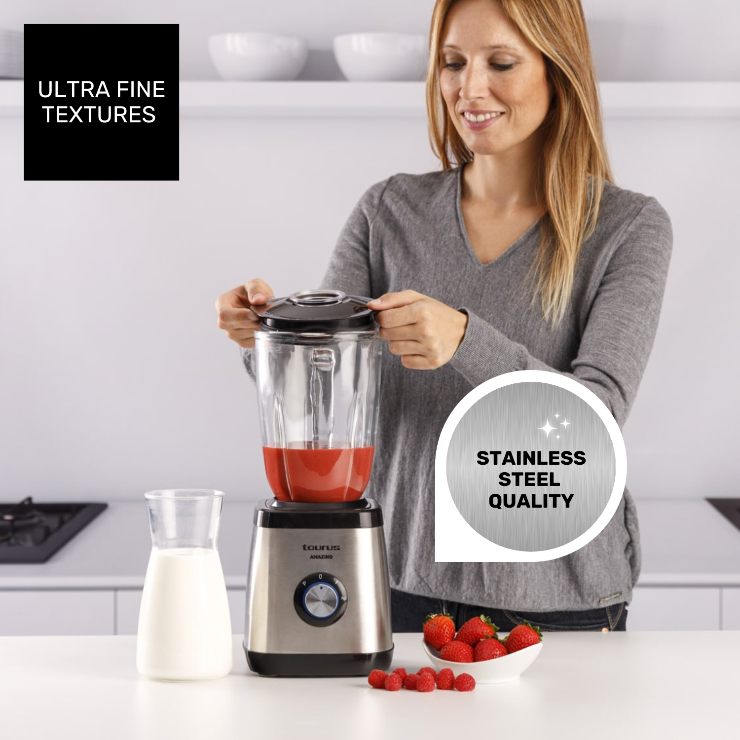 Mujer con licuadora, llena de jugo rojo, leche y bayas cerca.