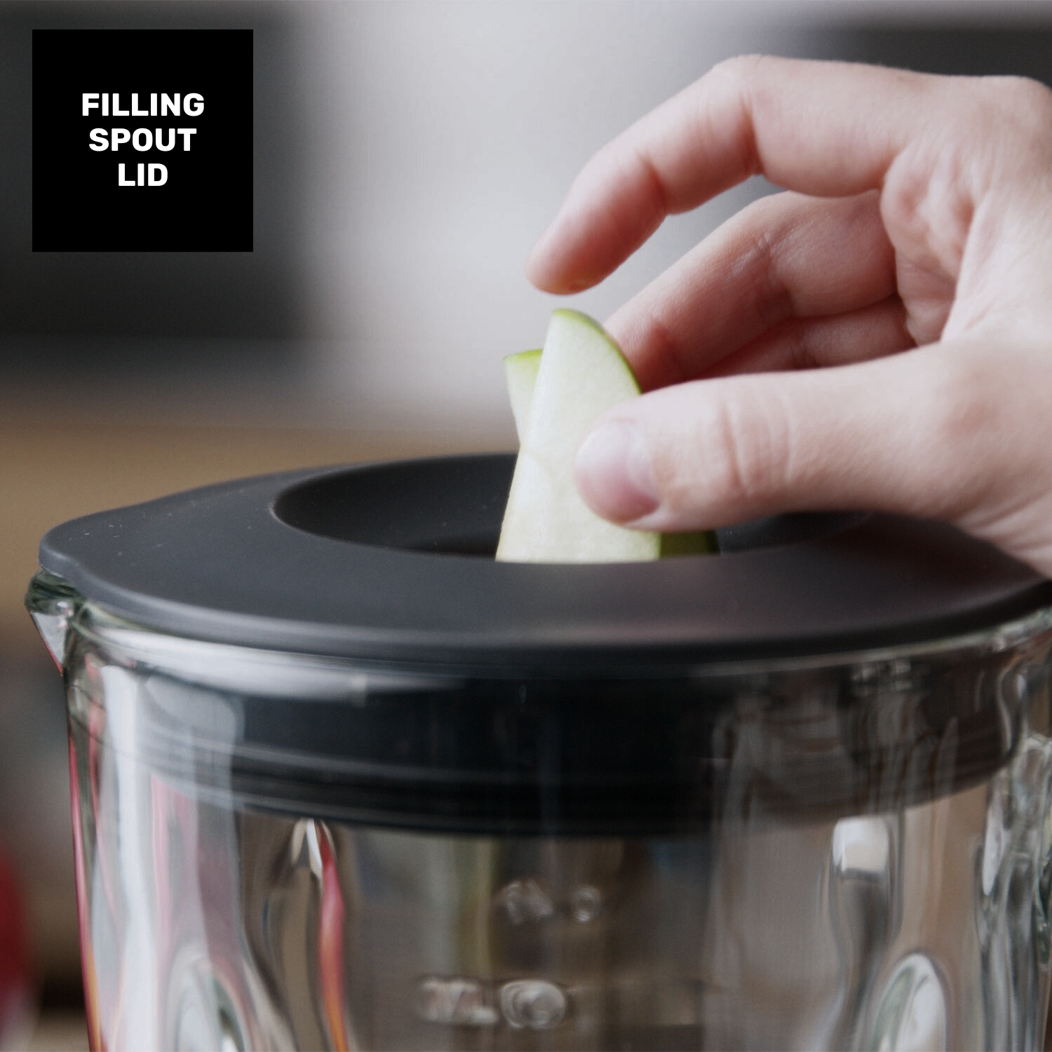 Una mano coloca una rodaja de manzana en el pico de llenado de un recipiente de vidrio.