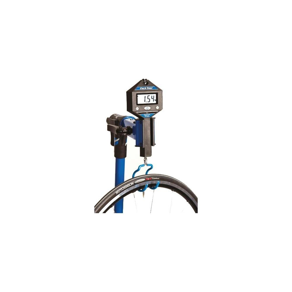 Una bilancia blu Park Tool mostra "1.54" mentre pesa uno pneumatico di bicicletta nero, appeso a un gancio blu.