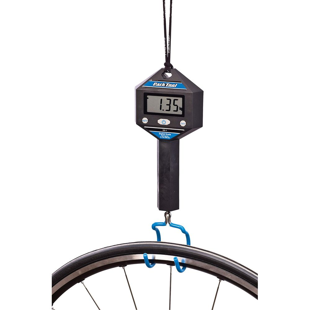 Una bilancia digitale nera con gancio blu pesa una ruota di bicicletta. La bilancia segna 1,35.