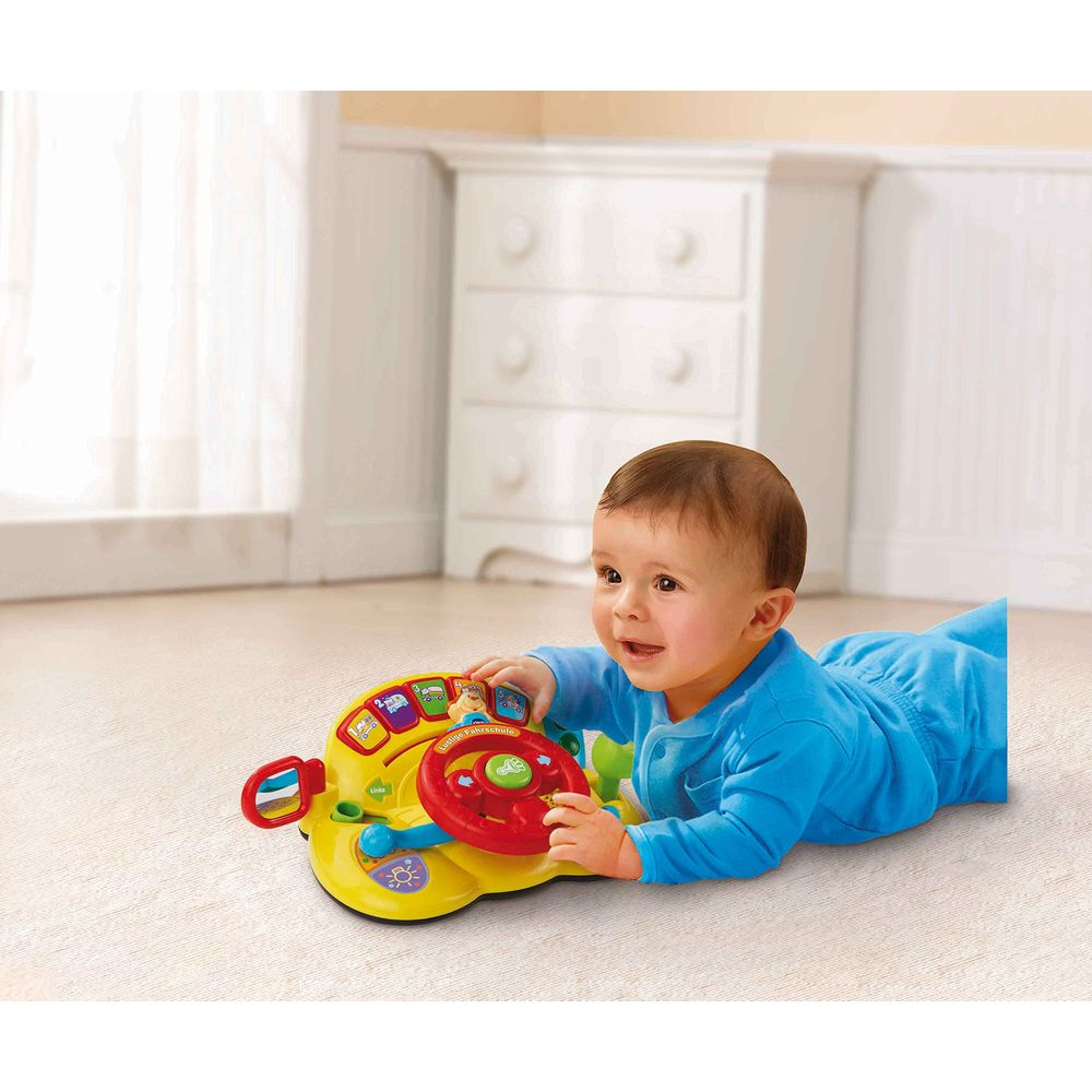 Ein Baby in blauer Kleidung liegt auf dem Bauch und spielt mit einem gelben Spielzeuglenkrad.