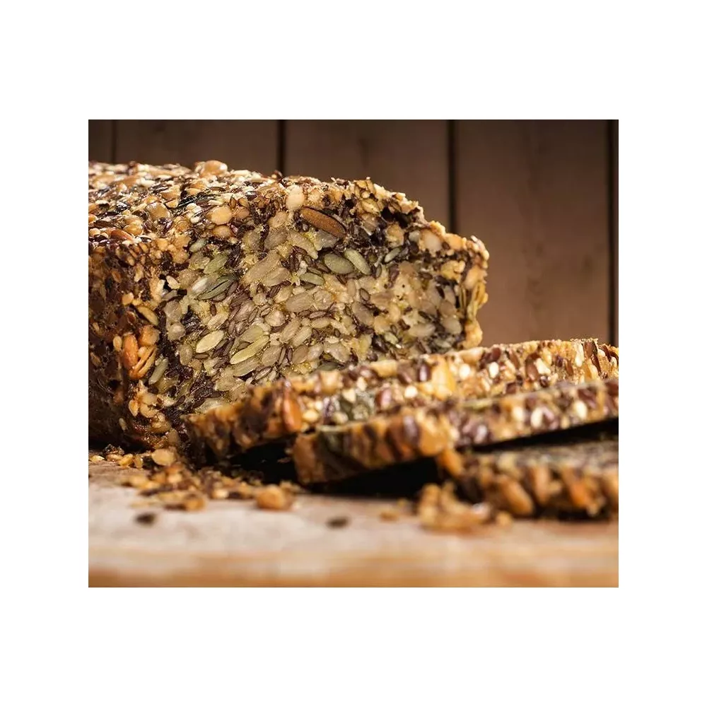 Ein Laib geschnittenes, mit Körnern bedecktes Brot auf einem Holzbrett.