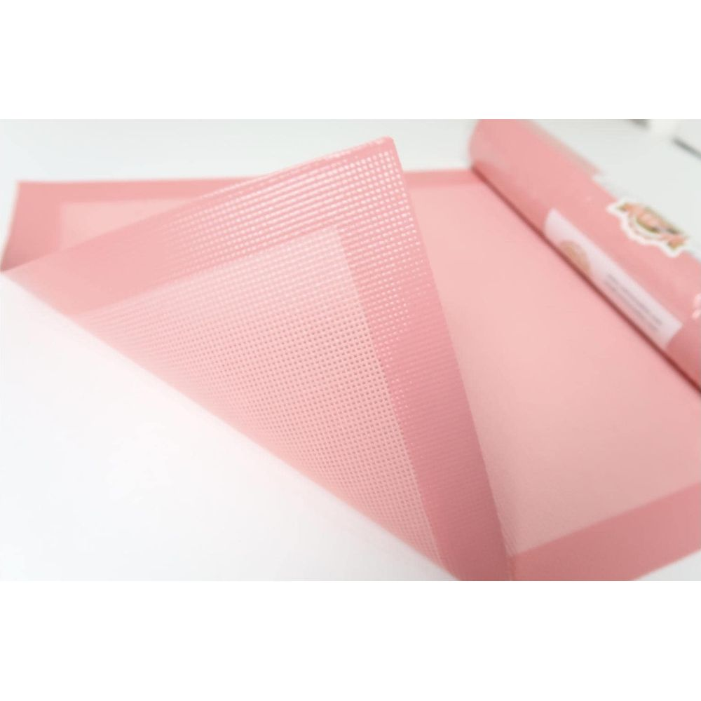 Un tapis de cuisson rose, partiellement roulé, avec une texture en grille.