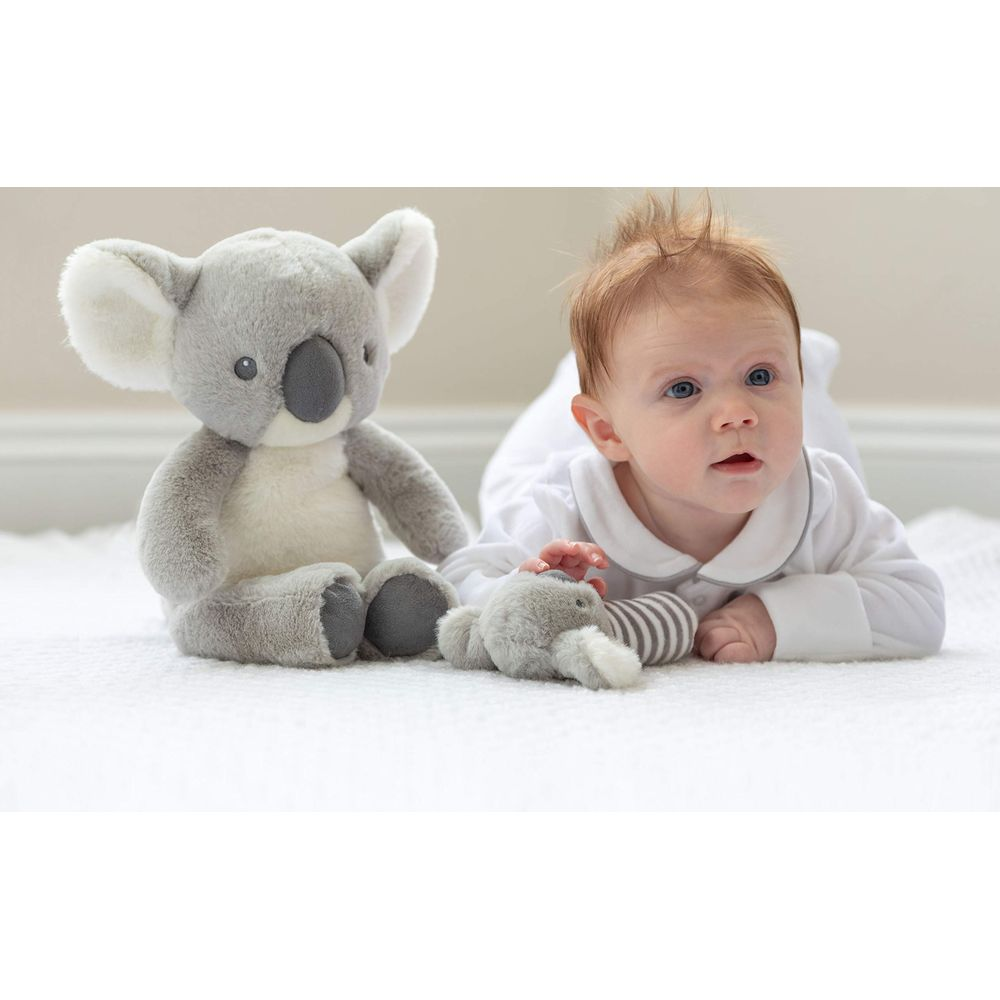 Un bambino è sdraiato a pancia in giù accanto a un peluche di koala e un piccolo elefante.