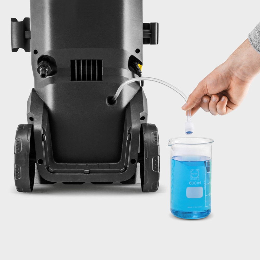 Wąż biegnie od myjki ciśnieniowej do zlewki z niebieskim płynem.