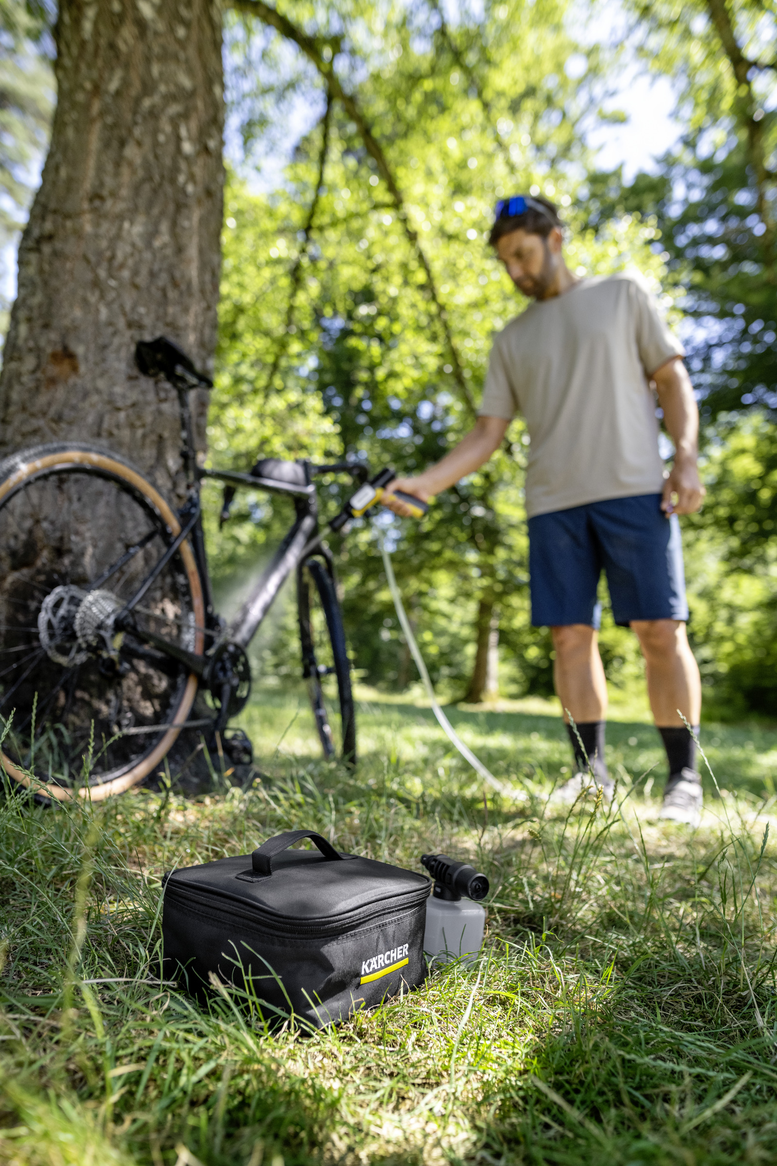 Man reinigt fiets met Kärcher apparaat in bos.