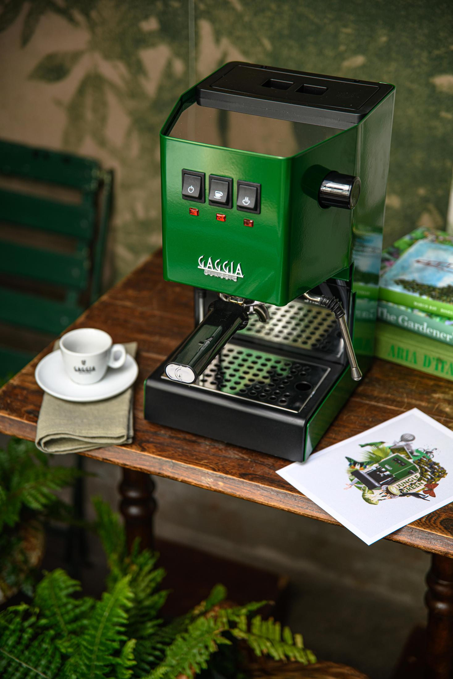 Een groene Gaggia espressomachine met kopje op schoteltje. Koffiethema kunst en boeken zijn in de buurt.