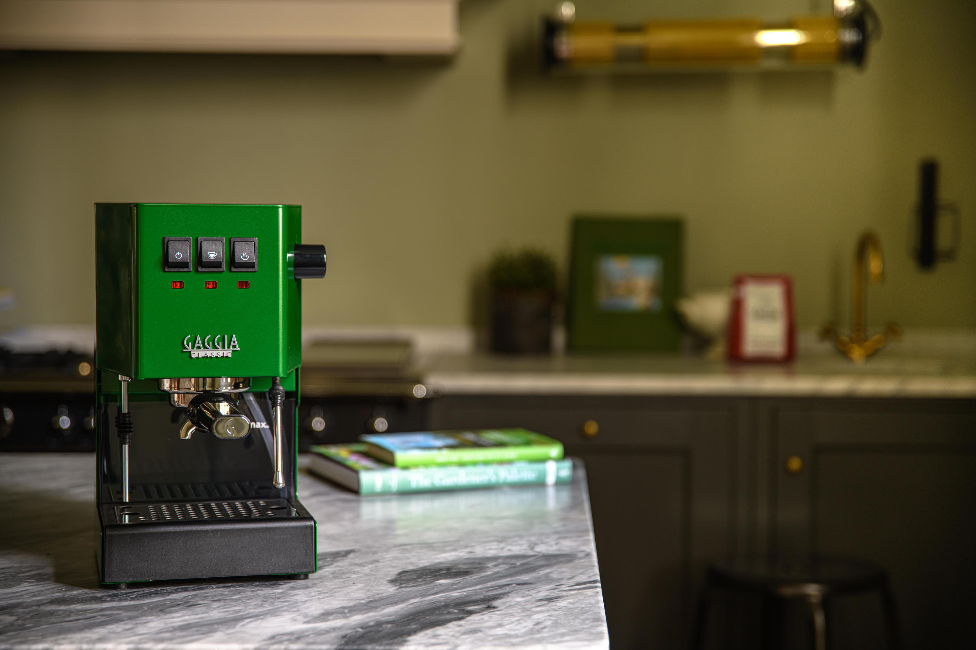 Een groene Gaggia espressomachine staat op een marmeren aanrechtblad.