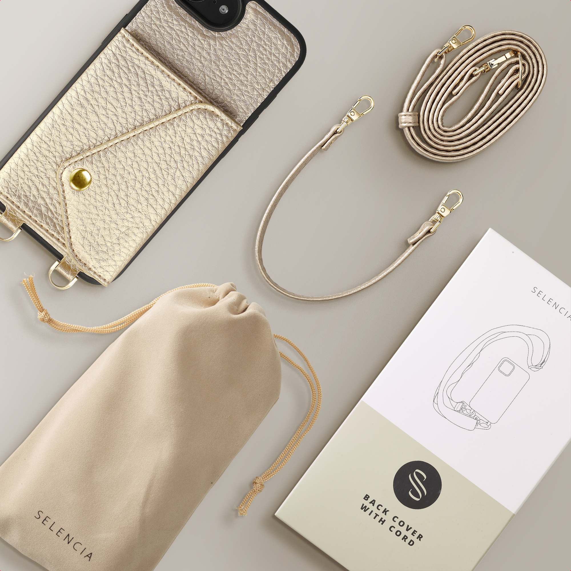 Coque dorée pour téléphone avec porte-cartes, cordon et pochette sur fond gris.