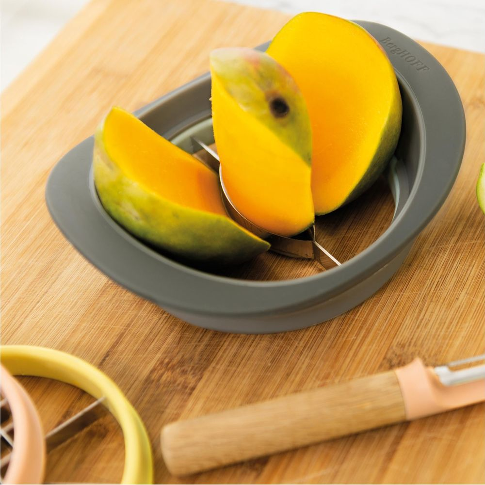 Un separatore di mango taglia un mango su un tagliere di legno.