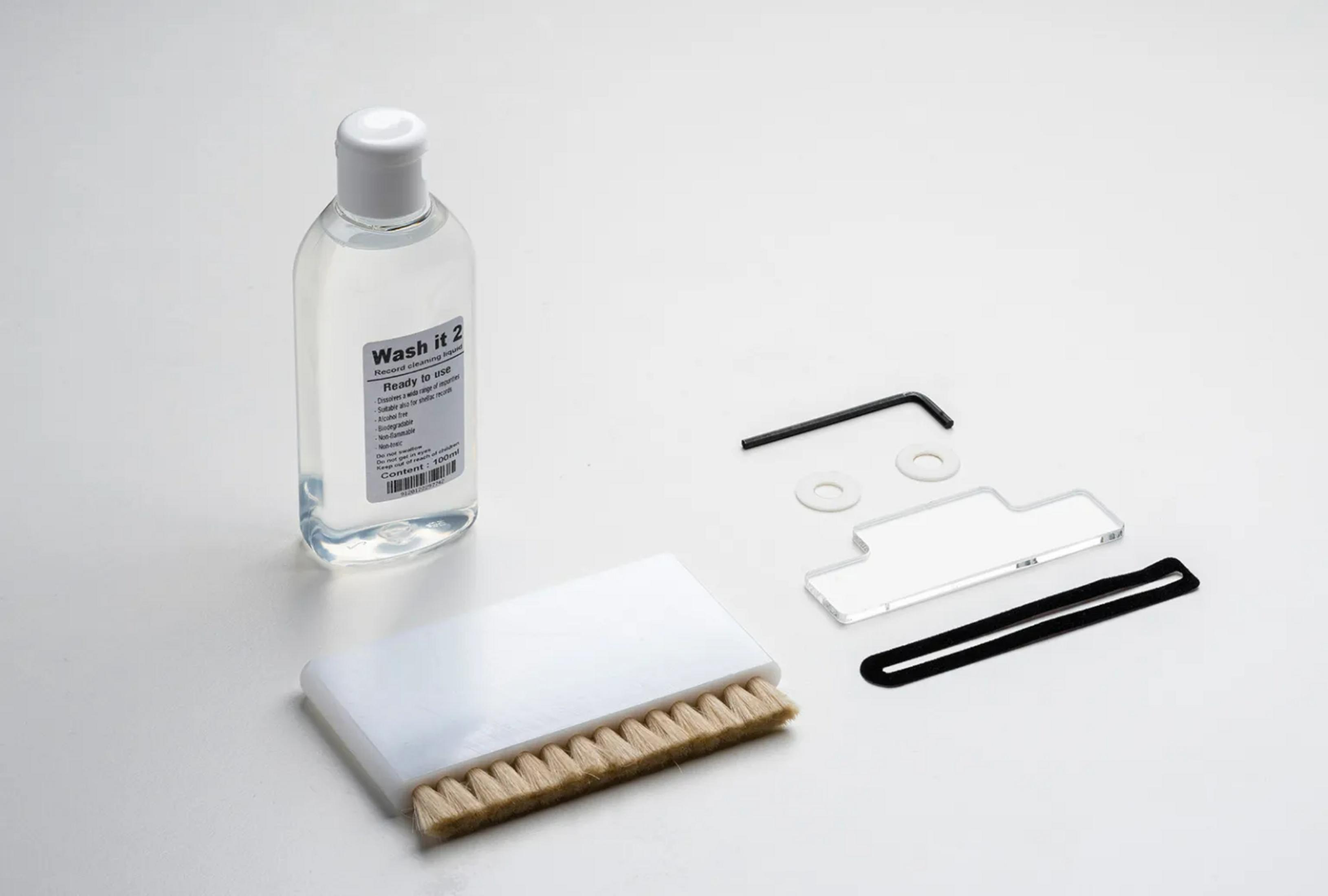 Butelka płynu do czyszczenia, szczotka i narzędzia na białym tle.