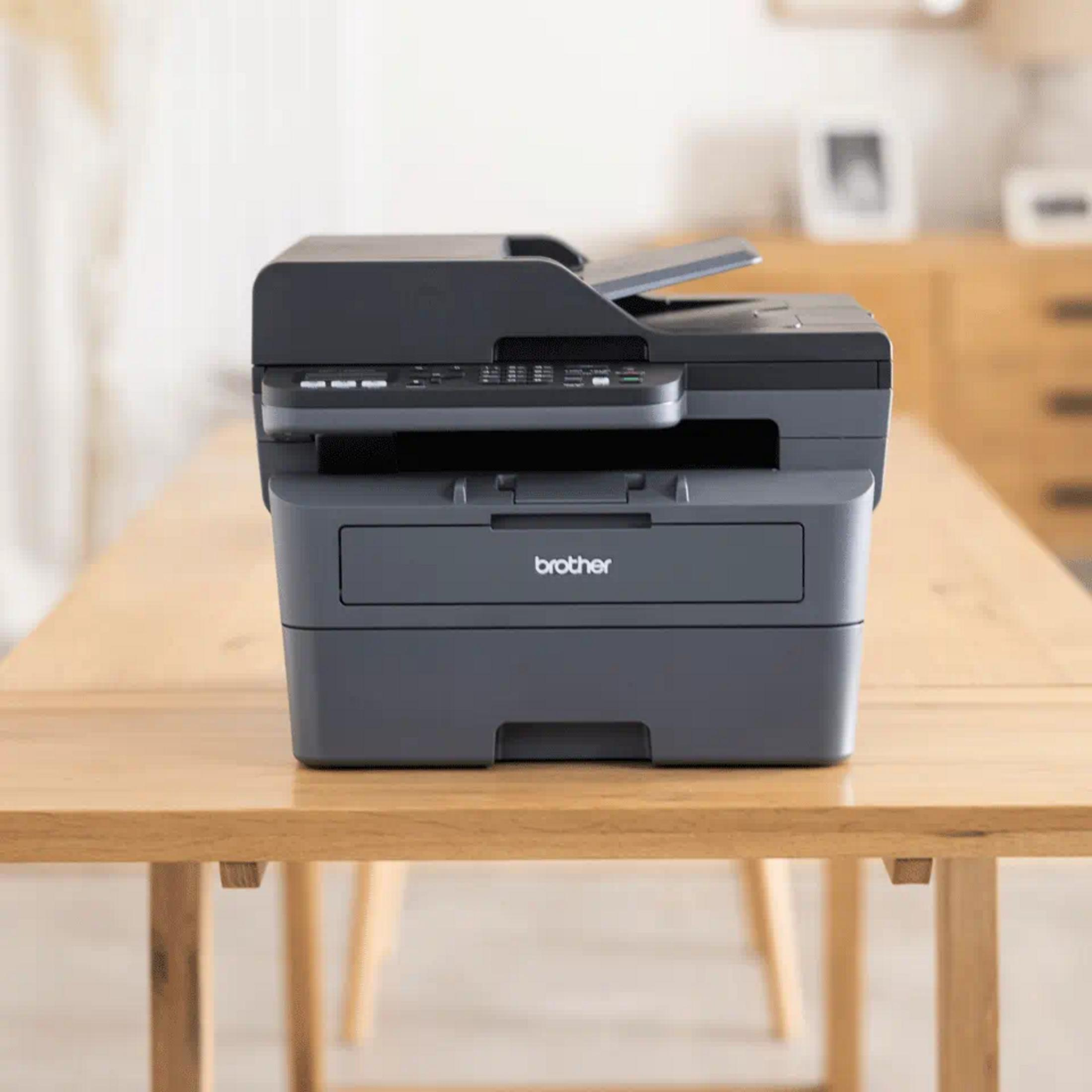 Ein dunkler Brother Drucker mit Scanner steht auf einem Holztisch.
