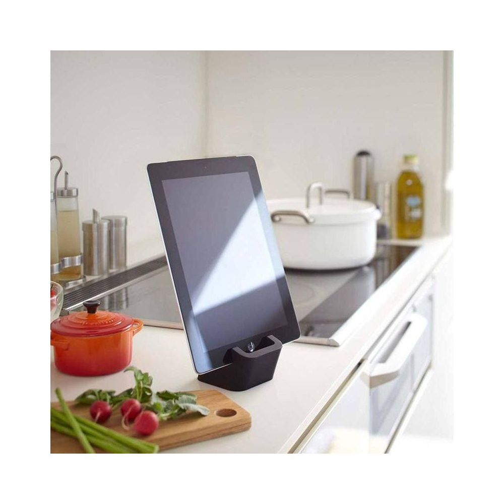 Un tablet si trova su un supporto in una cucina accanto a ravanelli e una pentola.