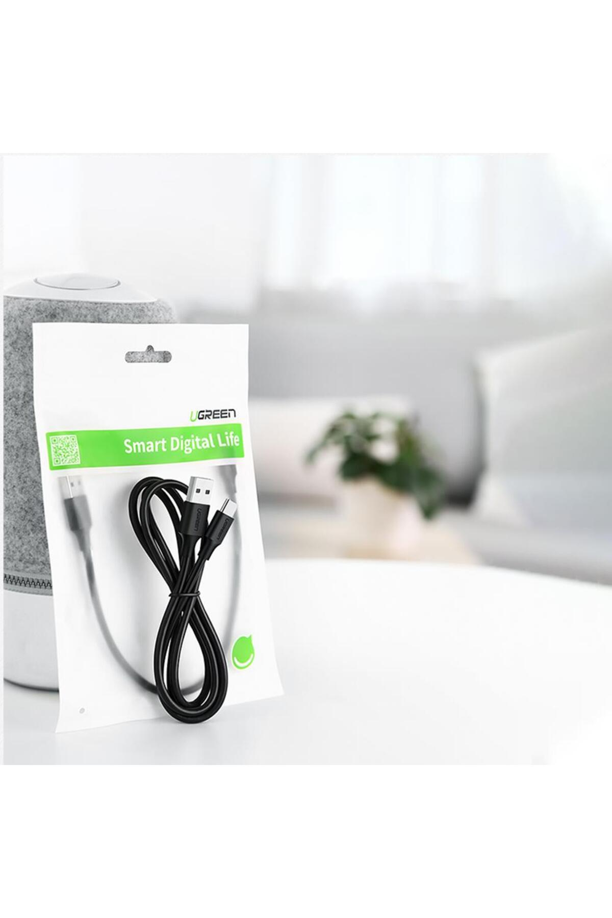 Gri hoparlör yanında masada ambalajında siyah USB kablosu.