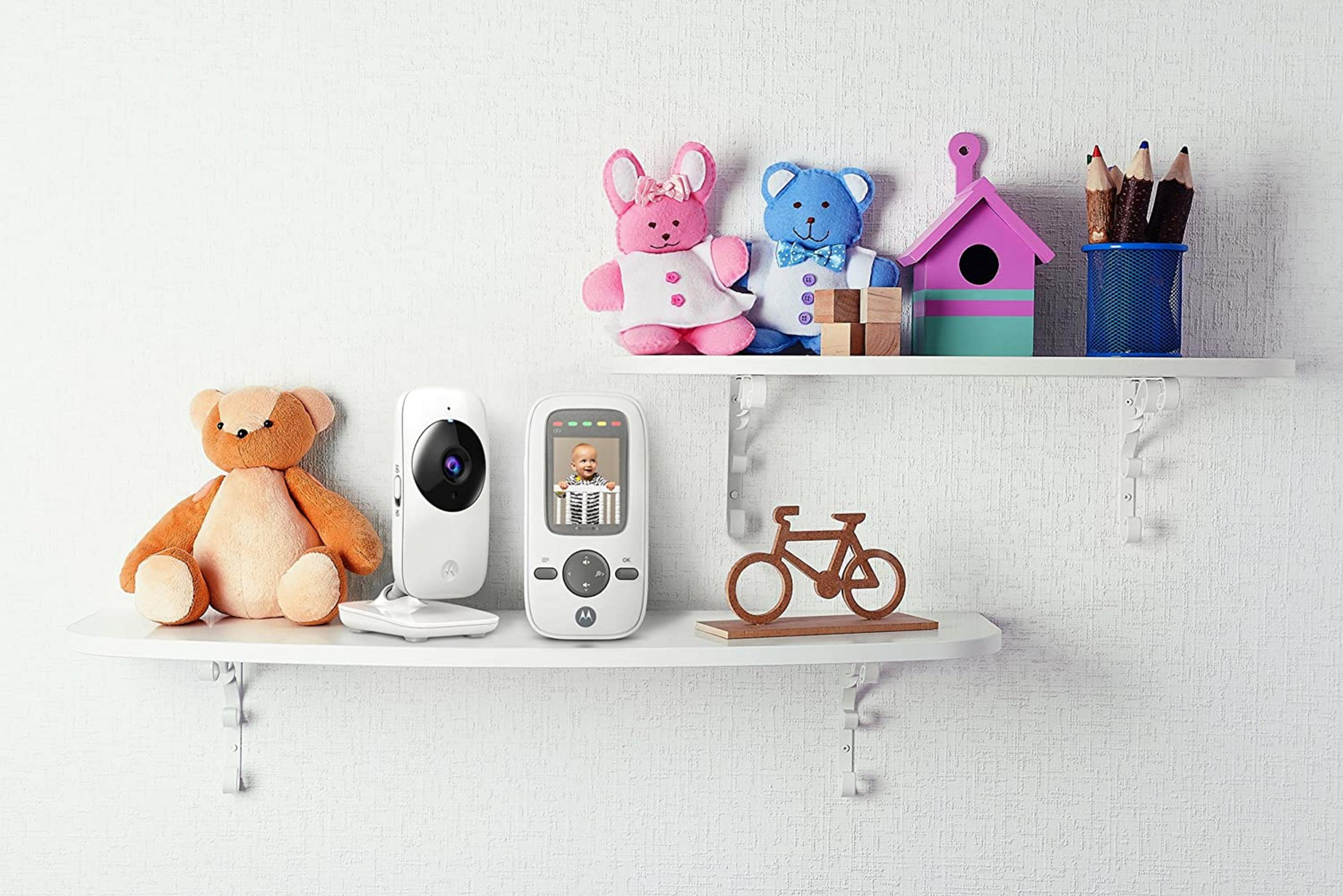 Ein Teddybär, ein Babyphone und Spielzeug auf einem Regal.