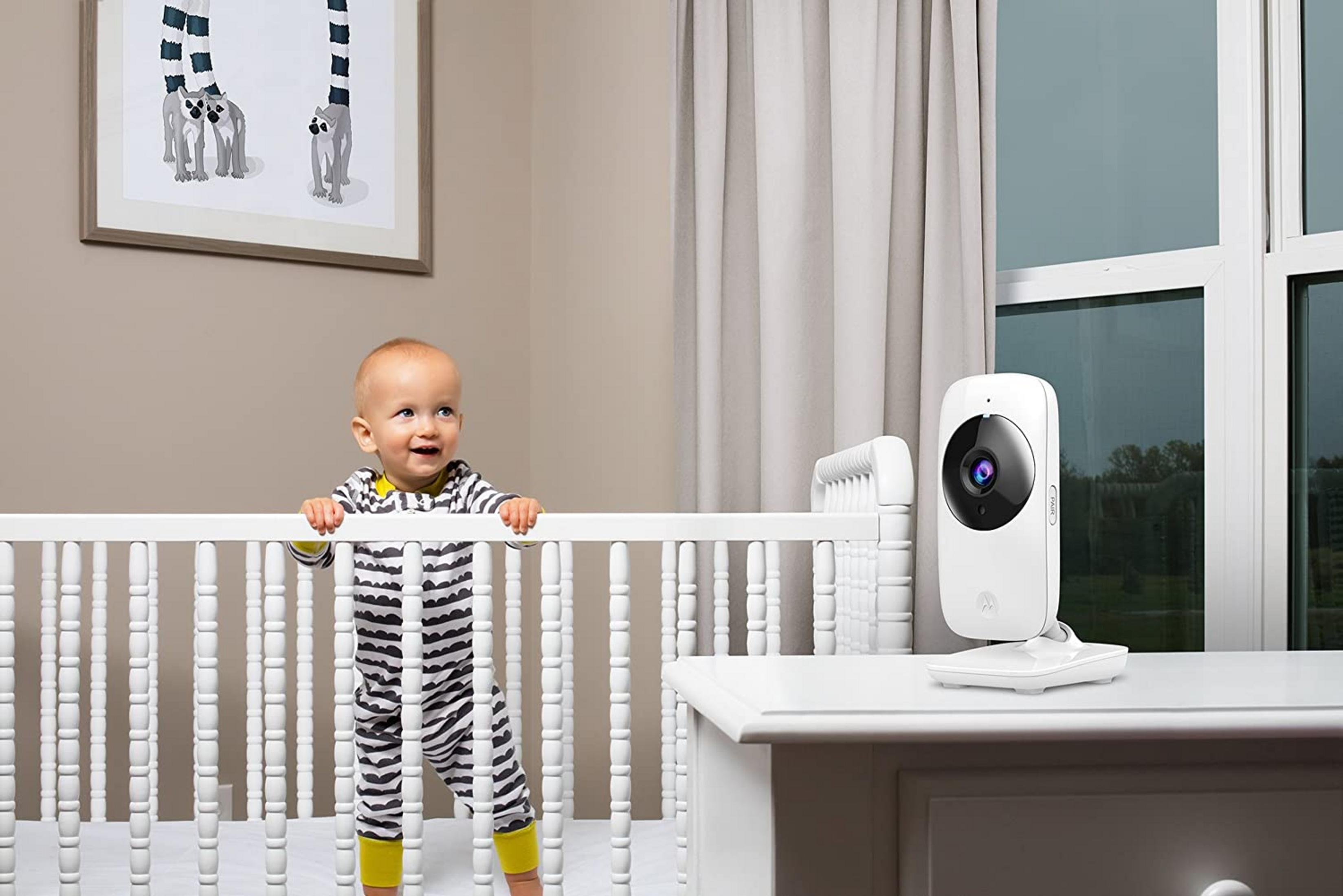 Baby im Gitterbett mit Babyphone und Lemuren-Wandkunst.