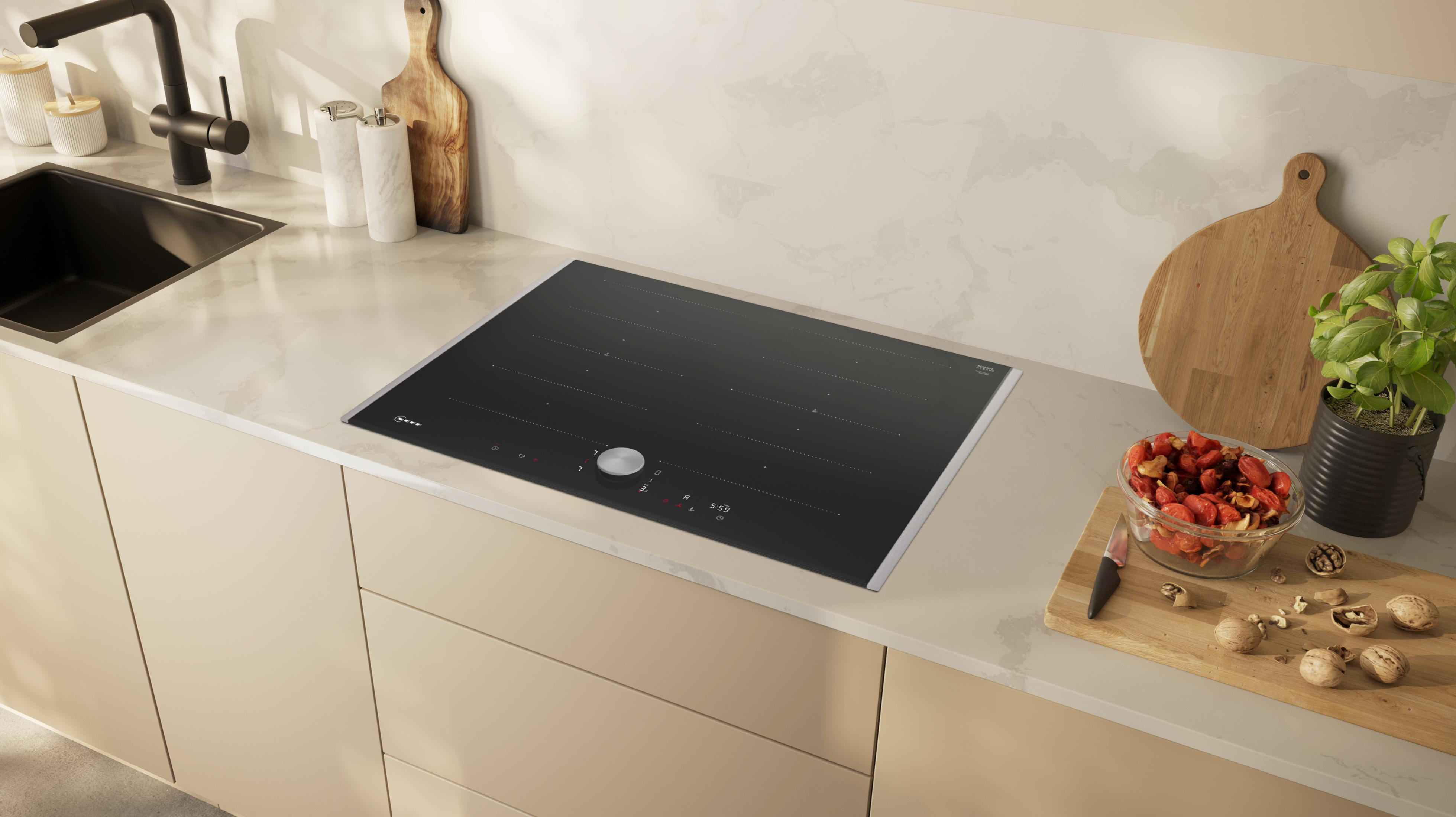 Cucina moderna con piano cottura a induzione, lavello, tagliere e frutta.