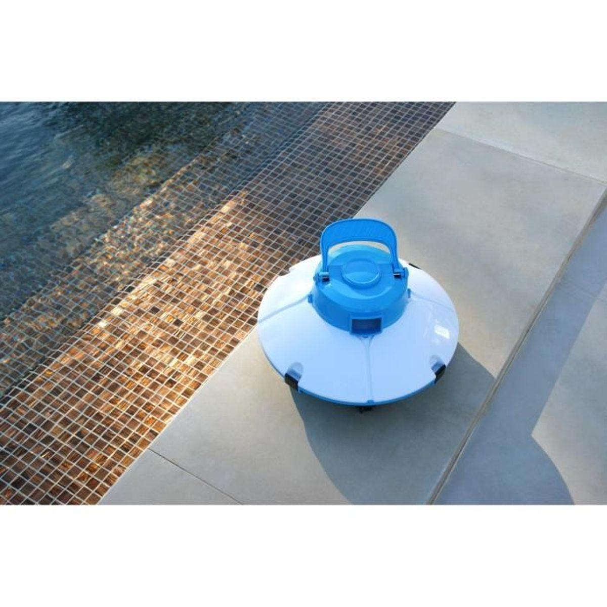 Un limpiador de piscinas blanco con asa azul está en el borde de la piscina junto al agua.