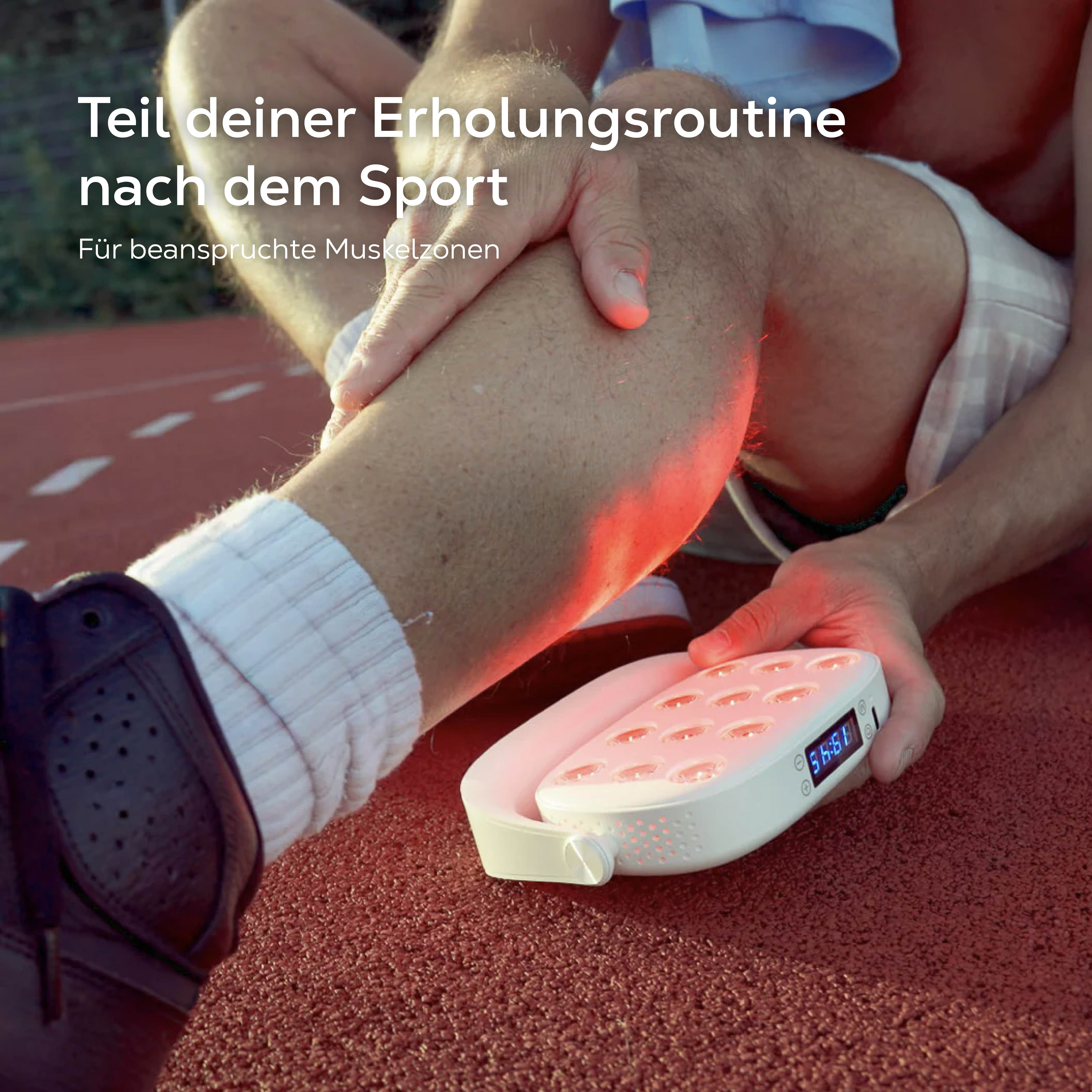 Ein Mann nutzt ein Rotlichttherapiegerät am Bein auf einem roten Sportplatz.