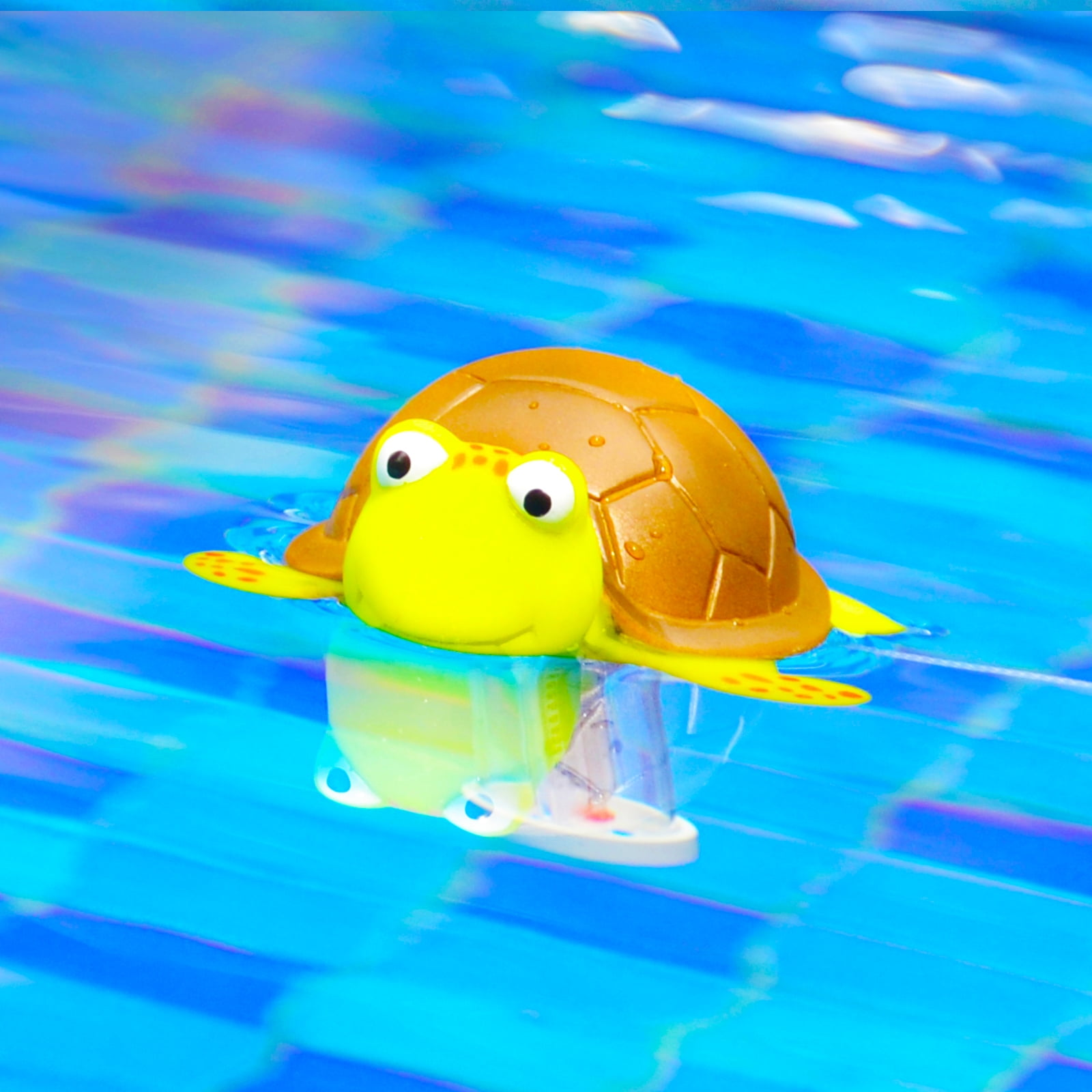 Eine gelbe Spielzeugschildkröte schwimmt in blauem Wasser mit einer reflektierenden Oberfläche.
