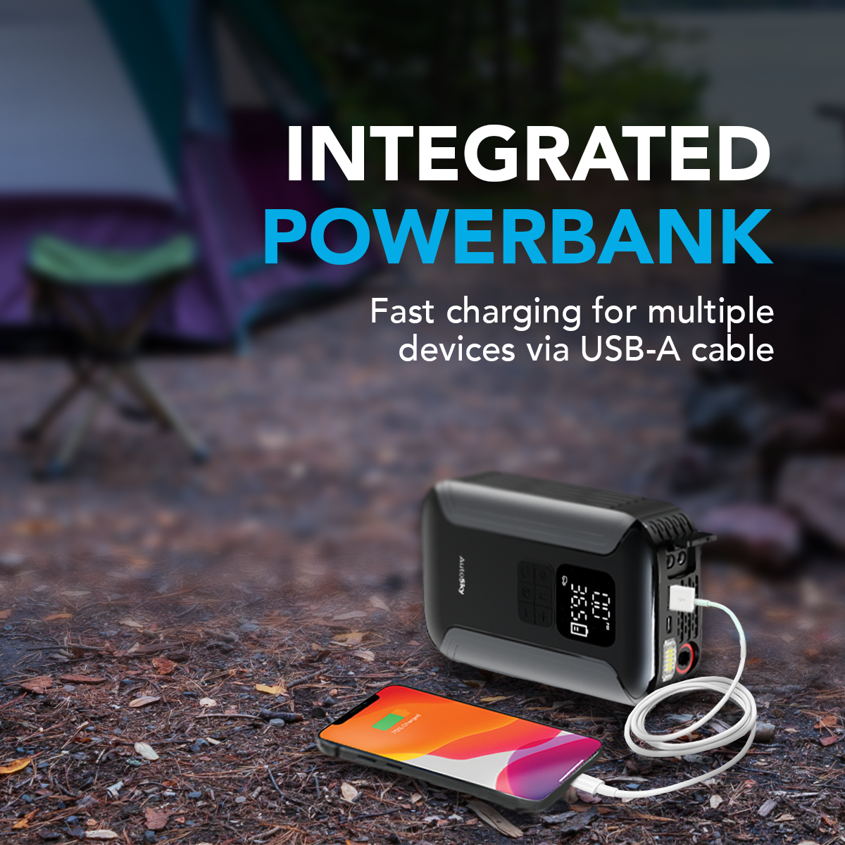 Power bank negra carga un teléfono, con una tienda de campaña al fondo.