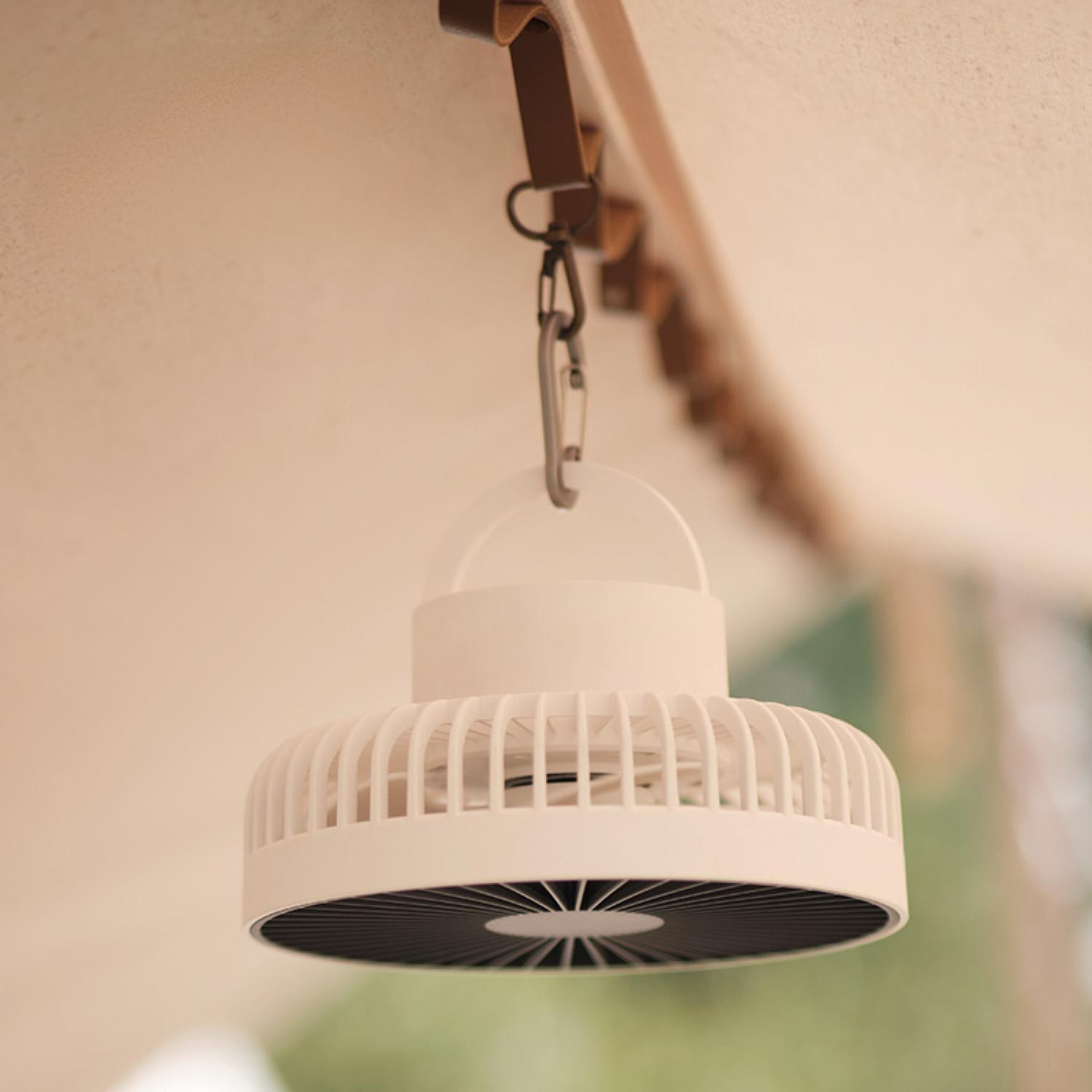 Ein weier Campingventilator hängt an einem Lederband und Karabiner.