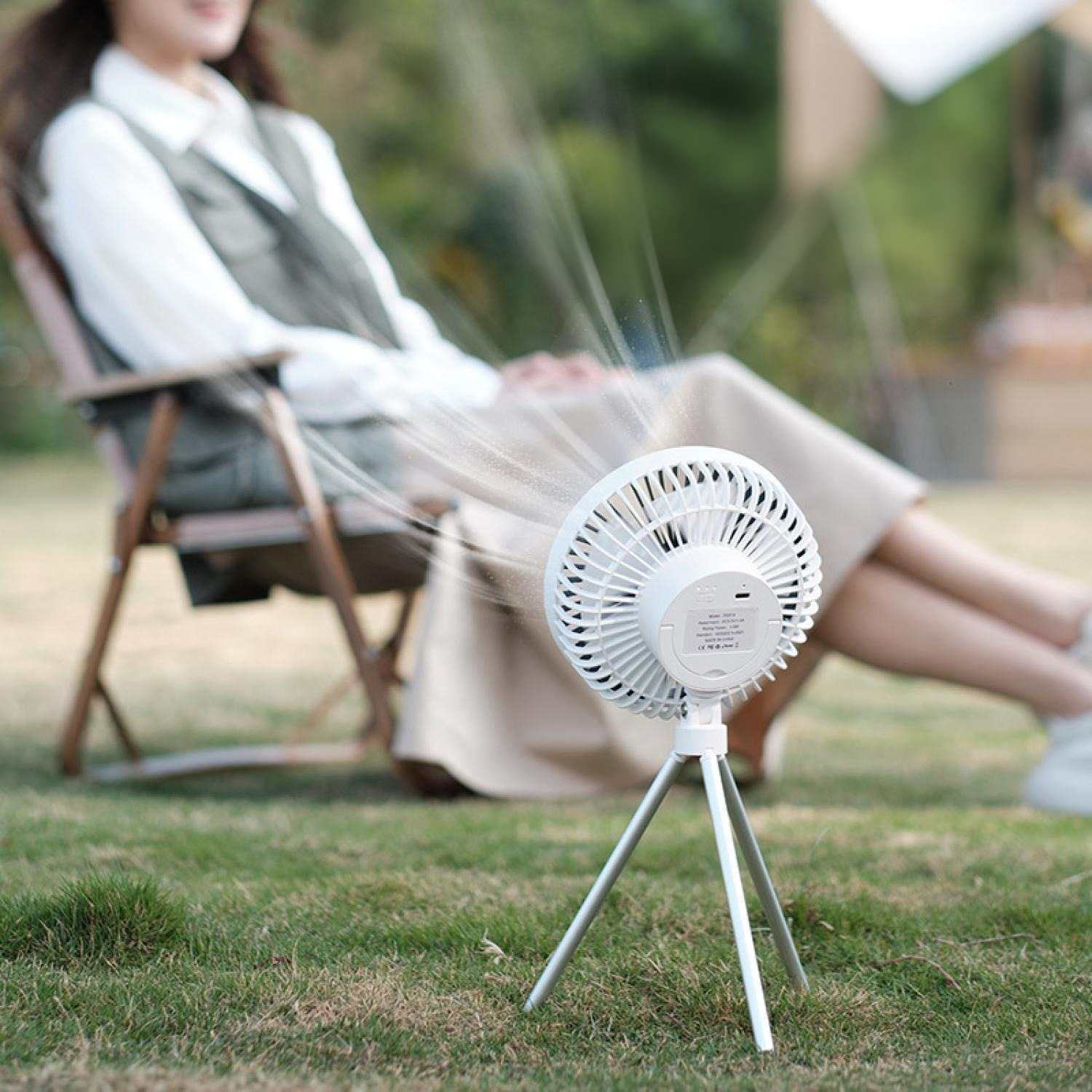 Ein weißer tragbarer Ventilator auf einem Stativ bläst Nebel auf eine Person im Freien.