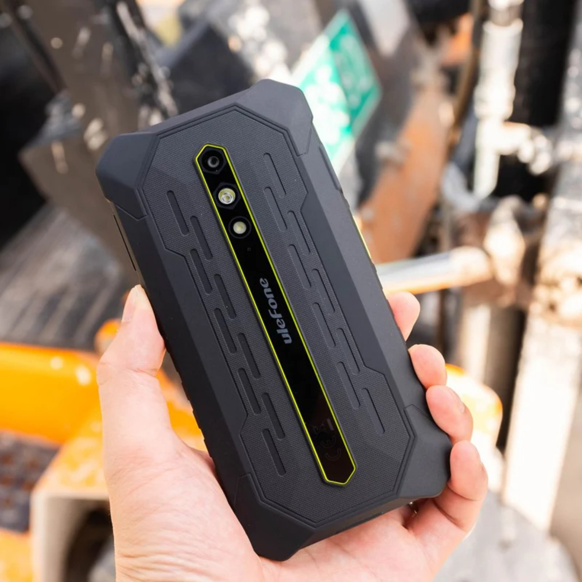 Ręka trzyma wytrzymały czarny smartfon Ulefone z żółtymi akcentami i dwoma aparatami.