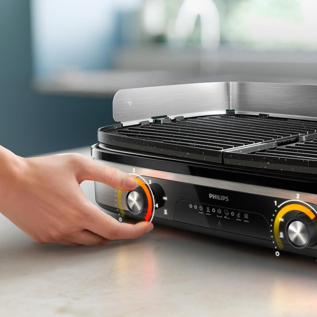 Hand dreht einen Temperaturregler an einem Philips Kontaktgrill.
