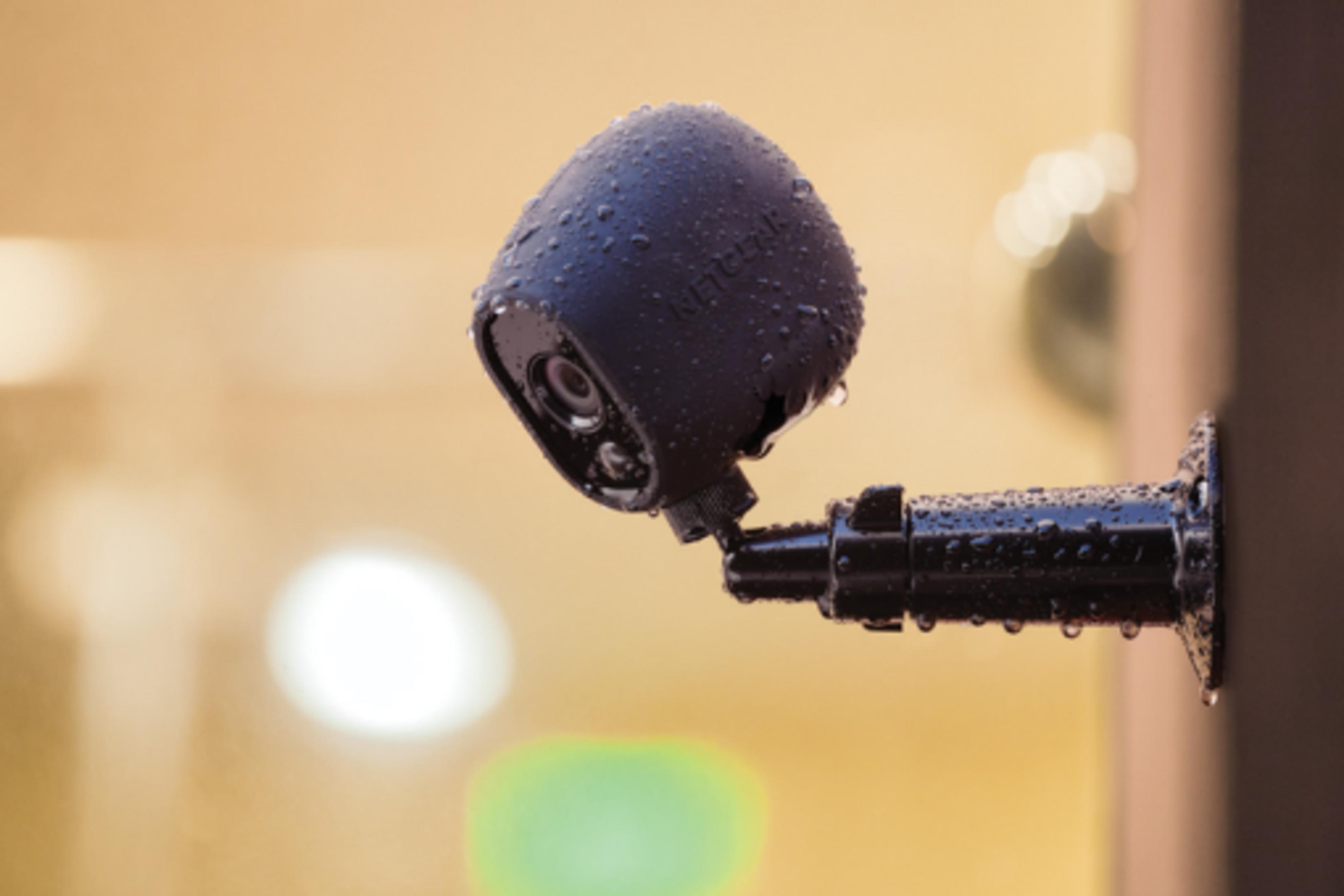 Una telecamera di sicurezza nera con gocce d'acqua è montata su un muro.