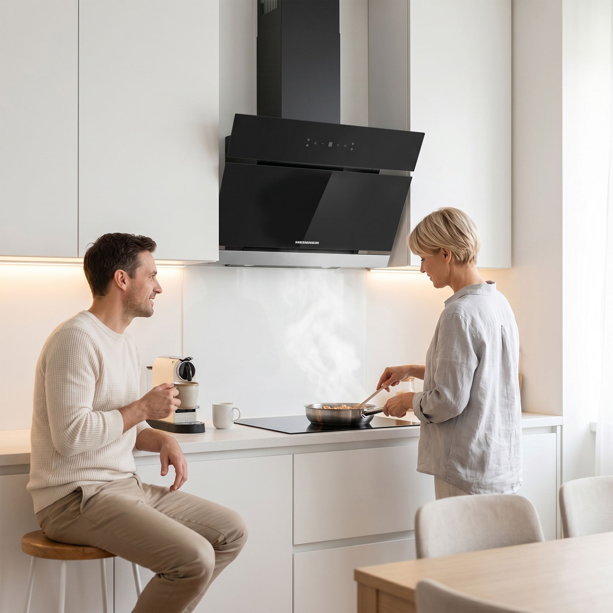 Man drinkt koffie, vrouw kookt in moderne keuken met afzuigkap.