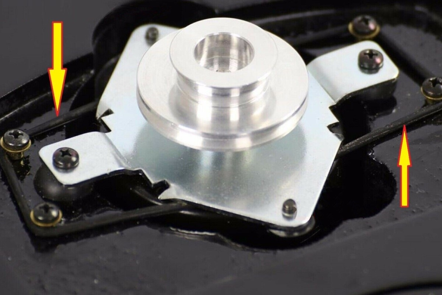 Zbliżenie metalowego elementu z dwiema żółtymi strzałkami wskazującymi na przewody.