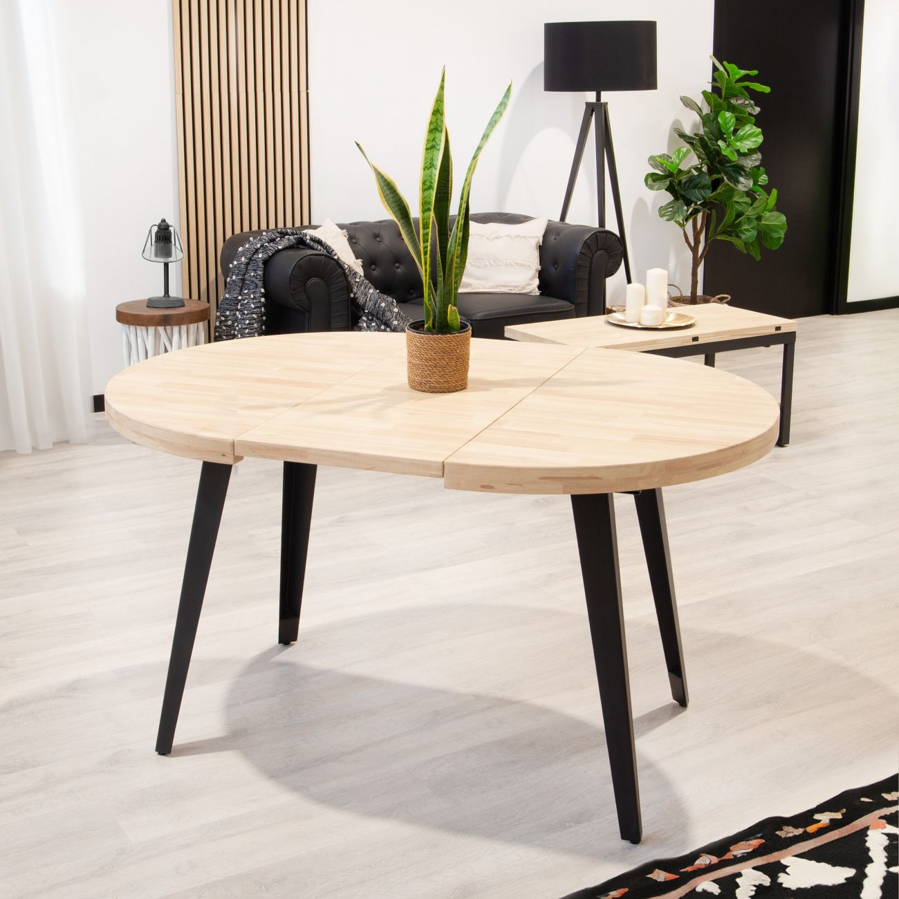 Una mesa de madera clara con patas negras está en un salón.