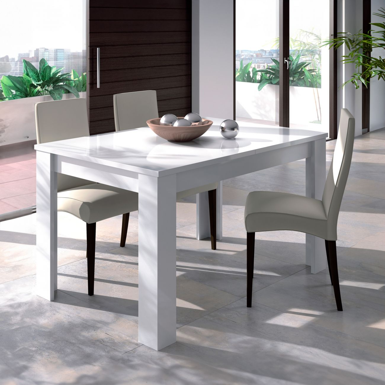Una mesa de comedor blanca con cuatro sillas en una sala luminosa con grandes ventanales.
