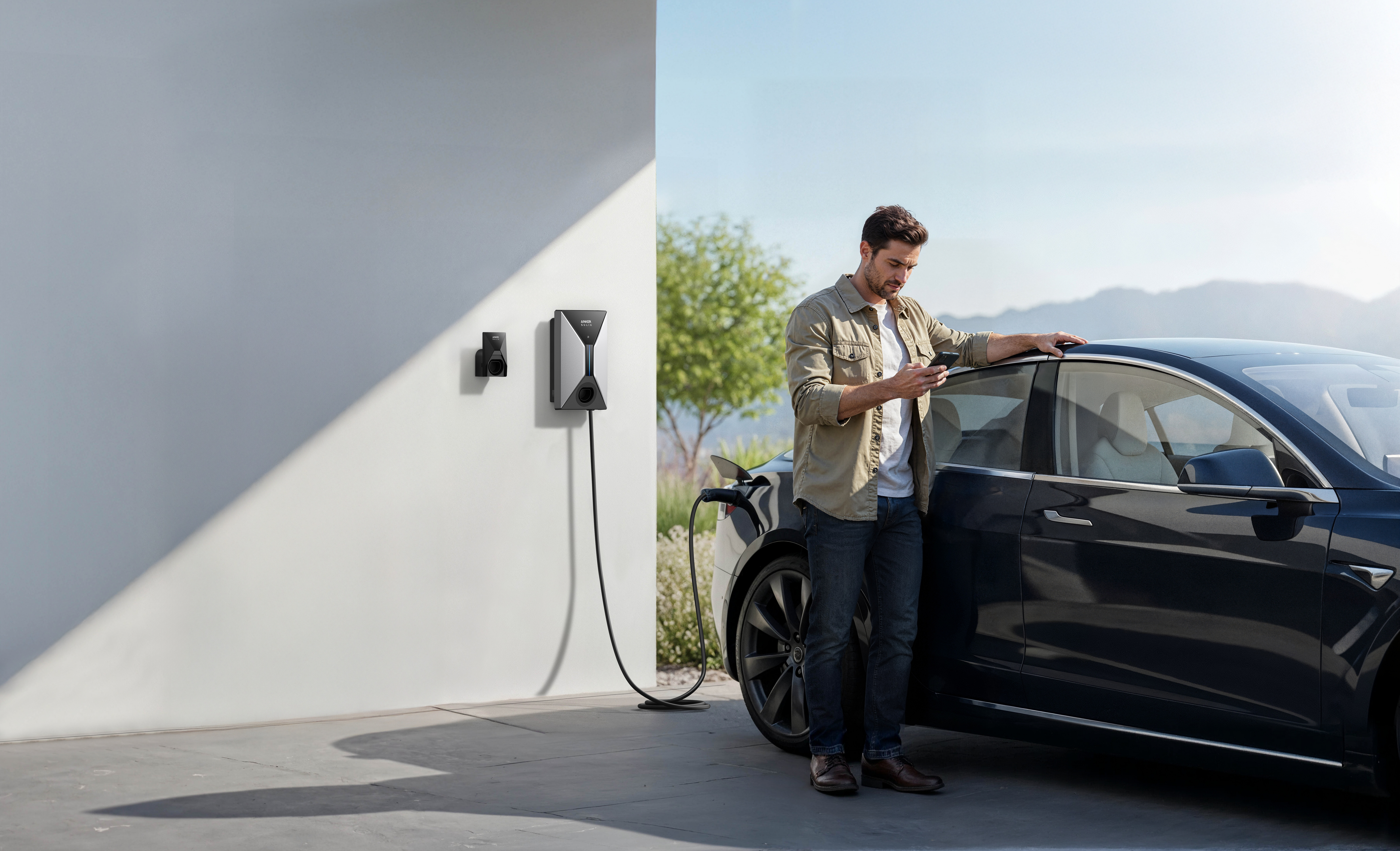 Homme utilise son téléphone près d'une borne de recharge de voiture électrique