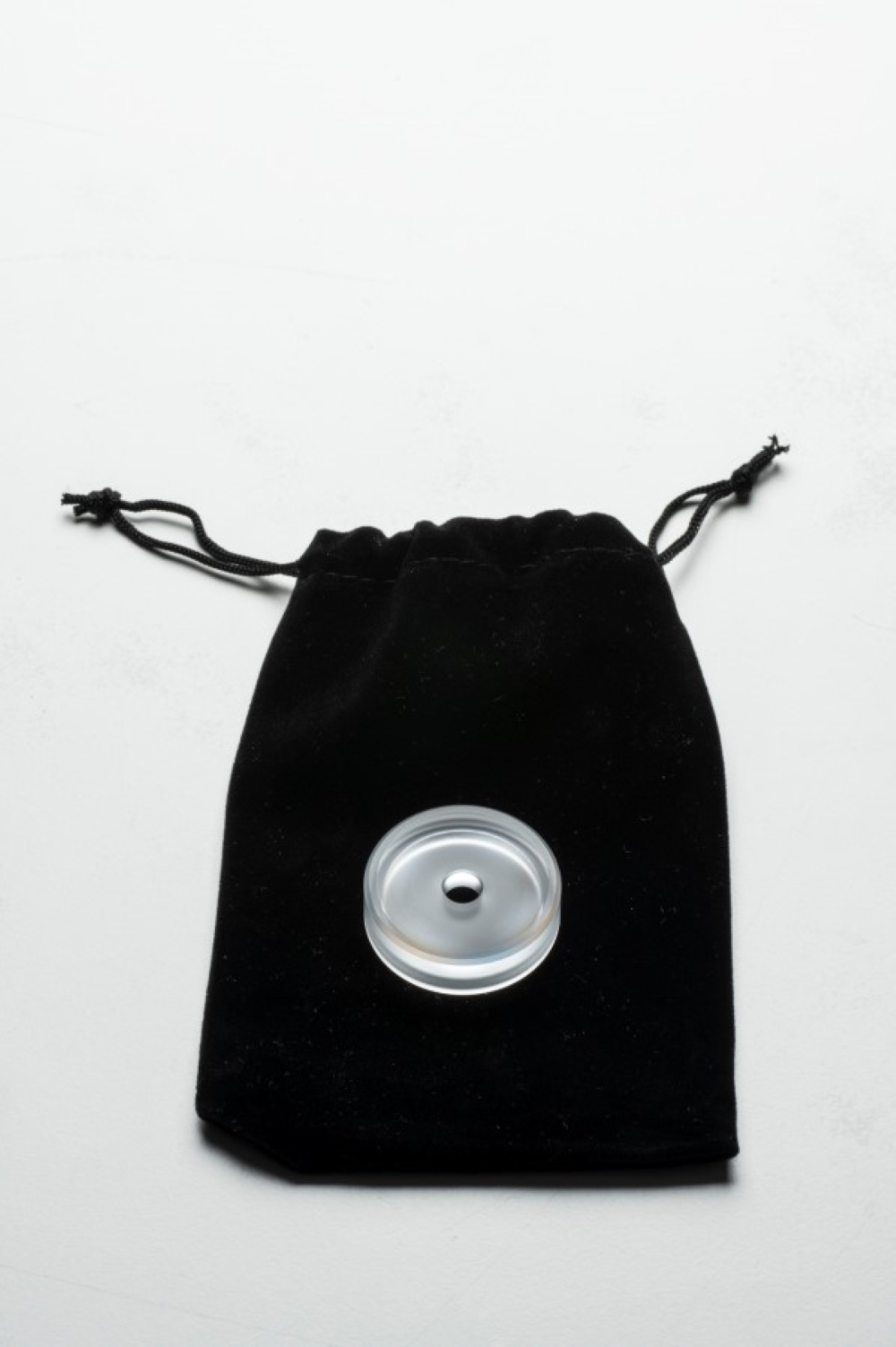 Czarny aksamitny woreczek z przezroczystym dyskiem pośrodku.