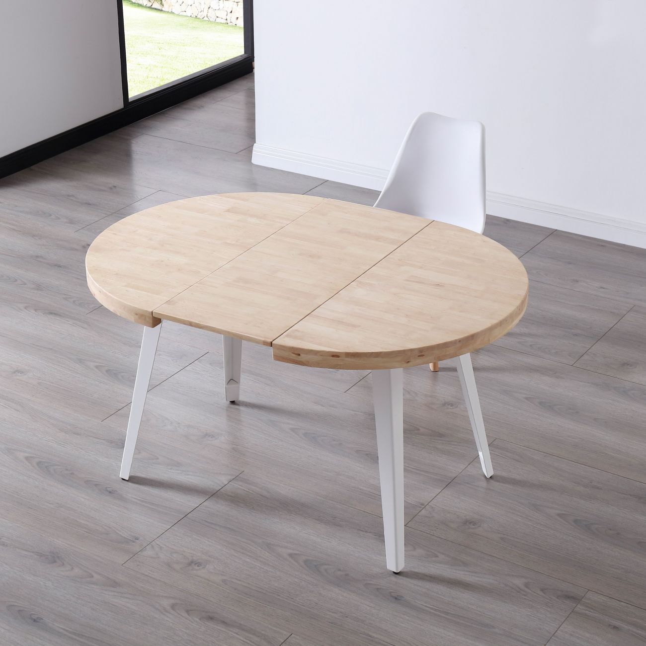 Una mesa ovalada de madera con patas blancas sobre suelo de madera.