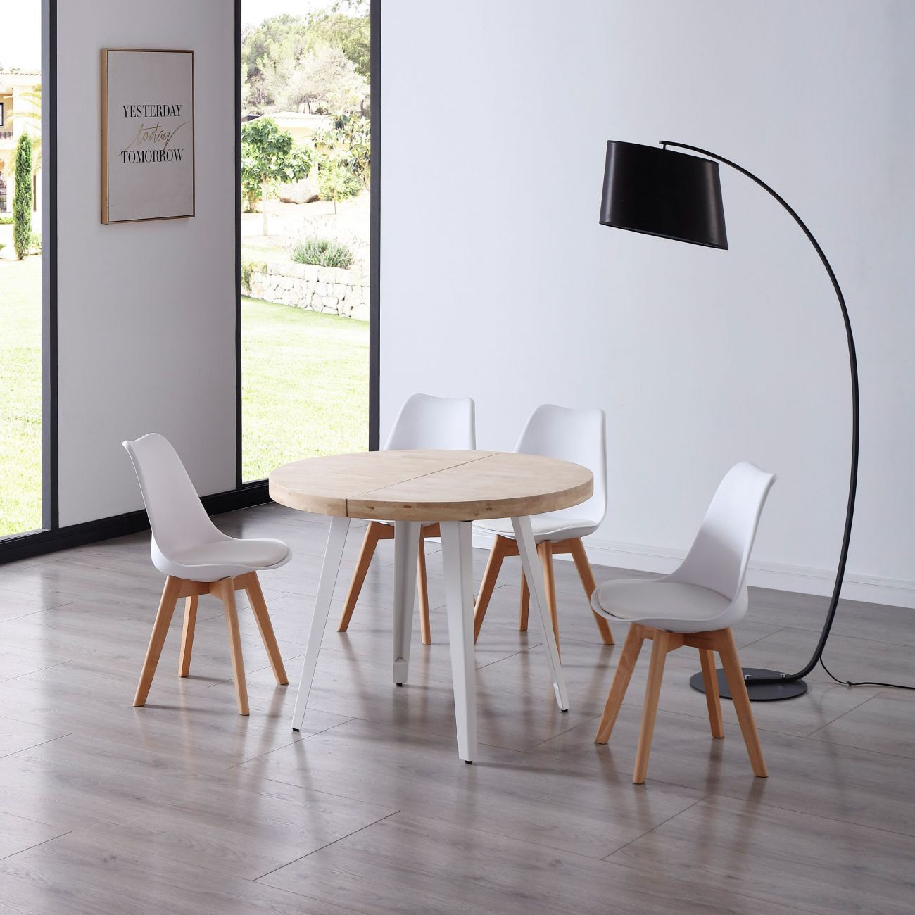Una mesa redonda de madera con cuatro sillas blancas en un comedor moderno.