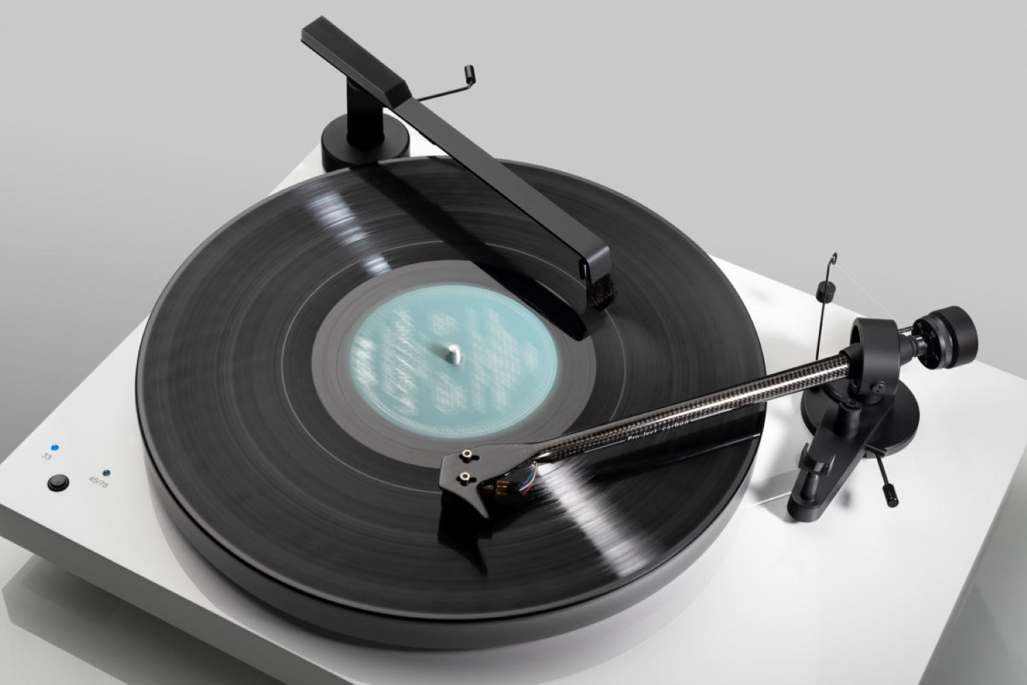 Biały gramofon z czarną płytą winylową i ramieniem, zbliżenie.