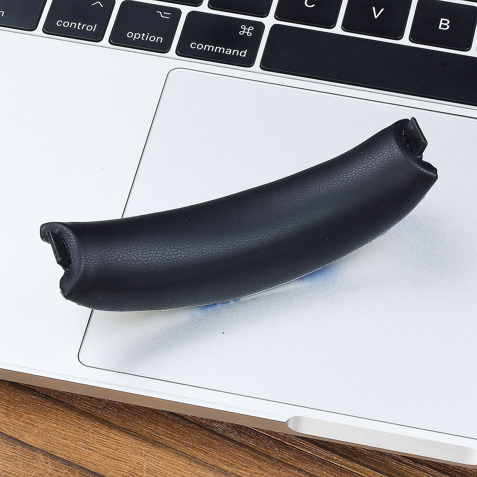 Un padiglione curvo nero poggia sulla tastiera argentata di un laptop.